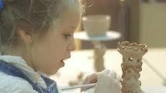 Young girl painting a clay piece