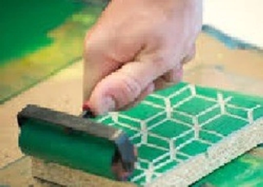Student rolling a green print over a canvas